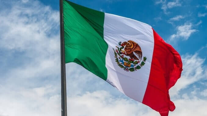 Flag of Mexico over blue cloudy sky