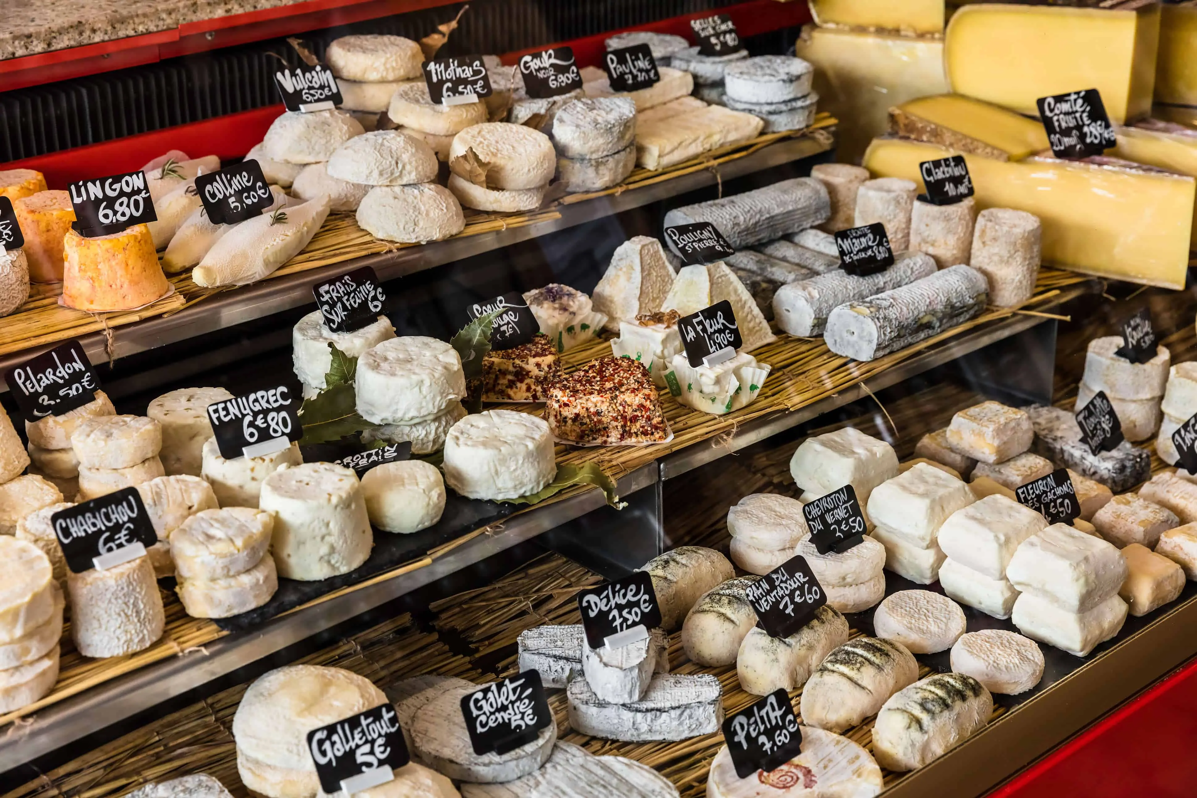 Different cheeses on the counter of a small store at the Aligre Market. Paris, France