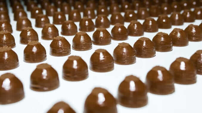 chocolate toppings on the conveyor of a confectionery factory close-up chocolate toppings on the conveyor of a confectionery factory close-up