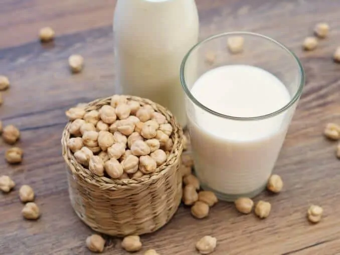 chickp's milk in a glass with a cup of raw whole chickpeas