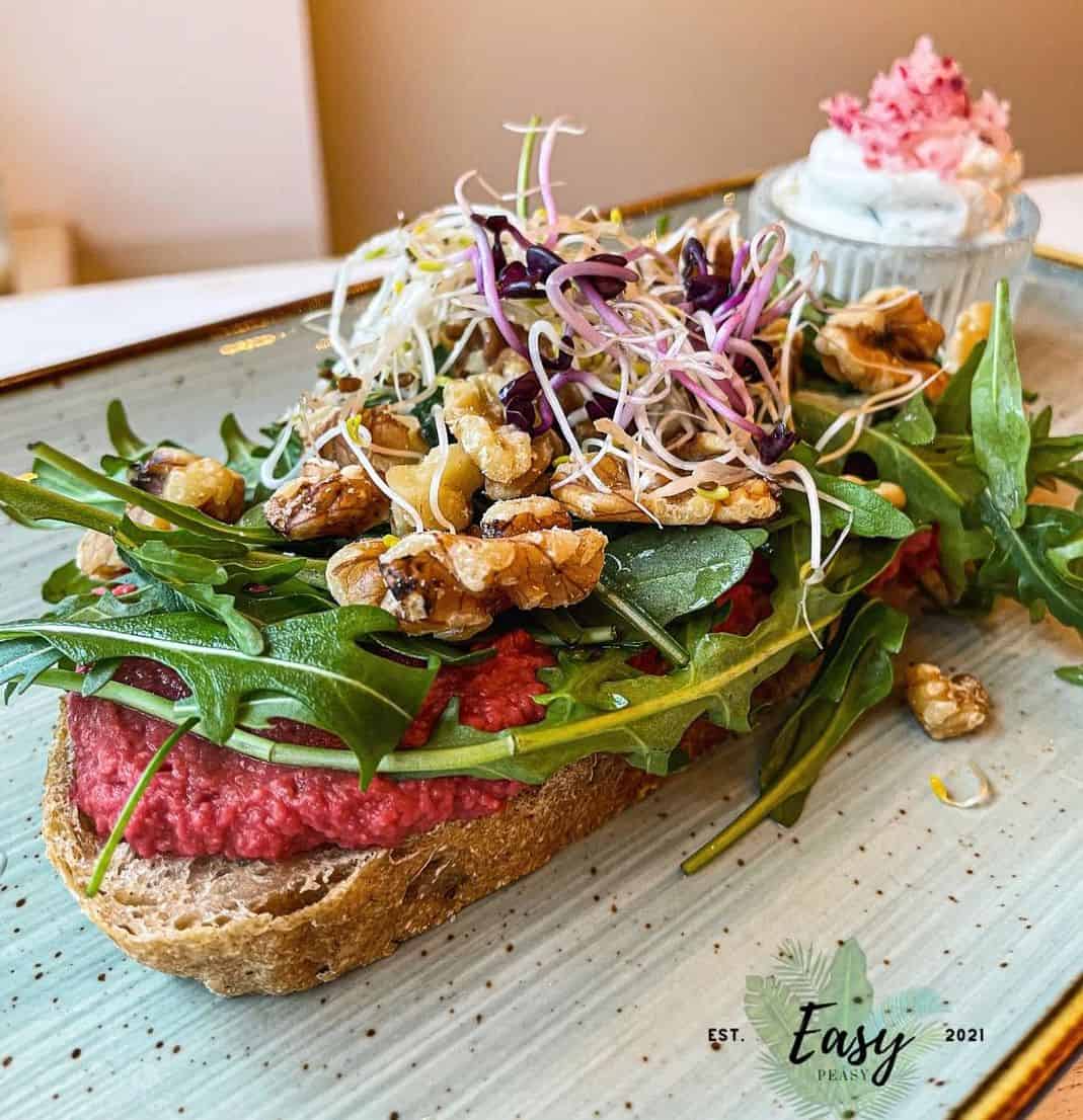 a vegan toast served with beetroot spread, walnuts and sprouts