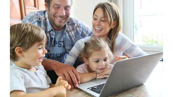 a family with two kids sits in front of a computer a family with two kids sits in front of a computer