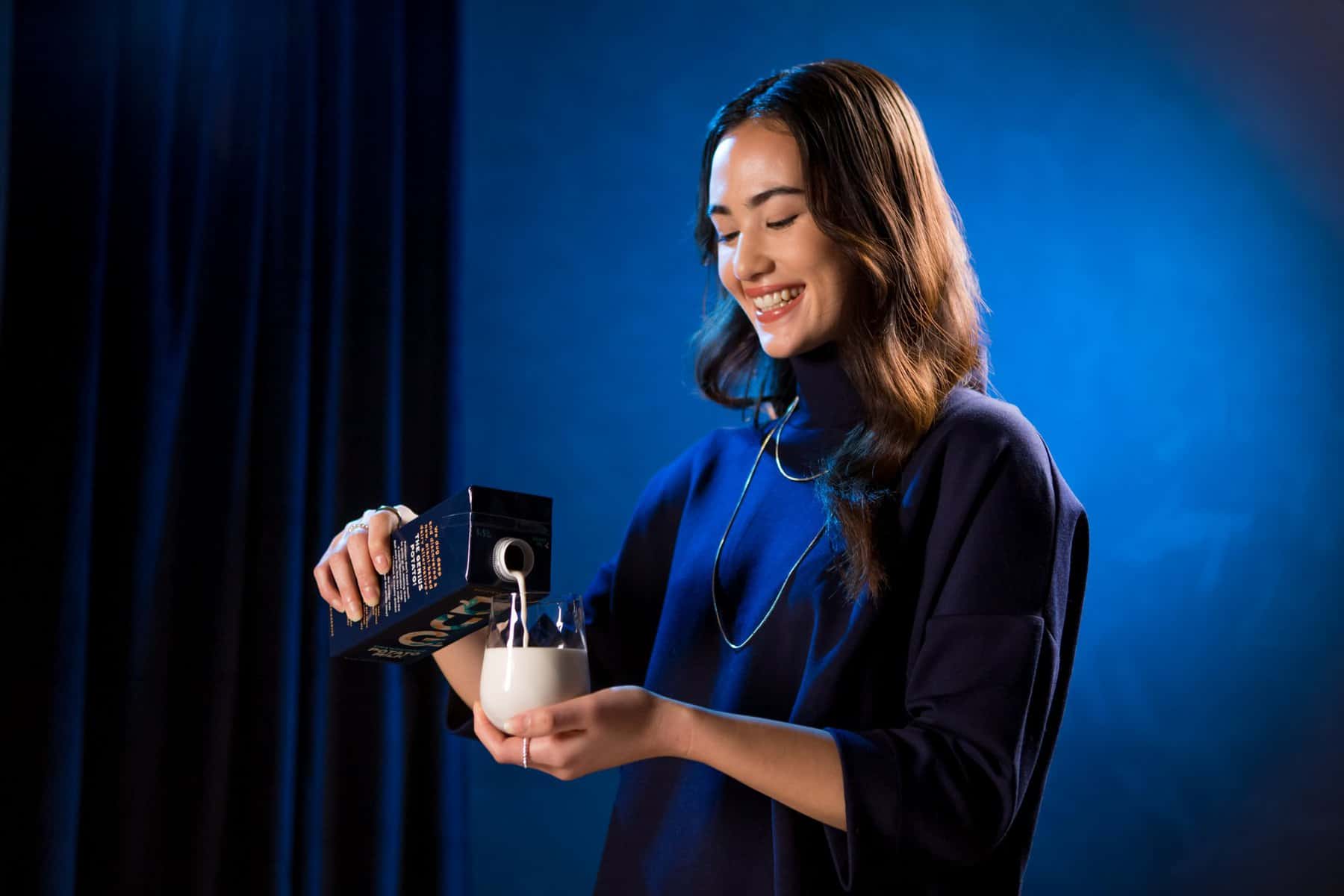 Lady pouring DUG milk on blue