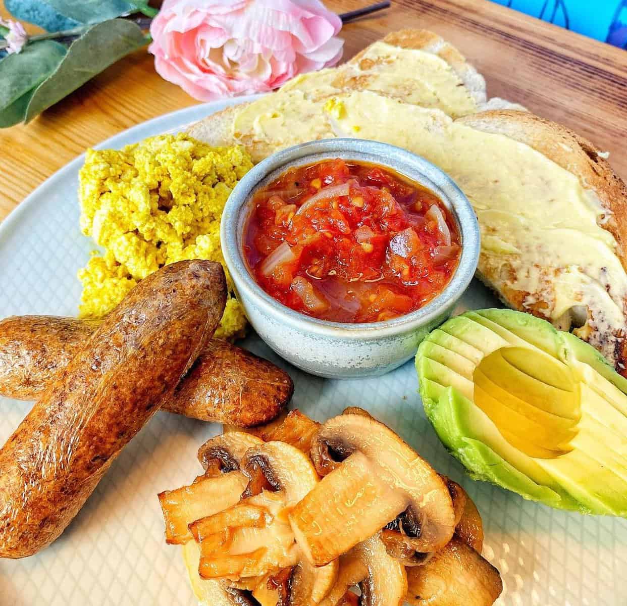 a plate of vegan breakfast with toasts. eggs, sausages and dipping sauce