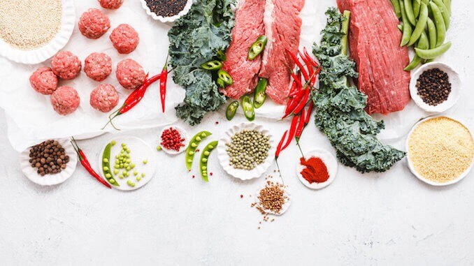 Variety raw beef cuts, meatbals and vegetables on table copy space overhead of cooking ingredients Variety raw beef cuts, meatbals and vegetables on table copy space overhead of cooking ingredients