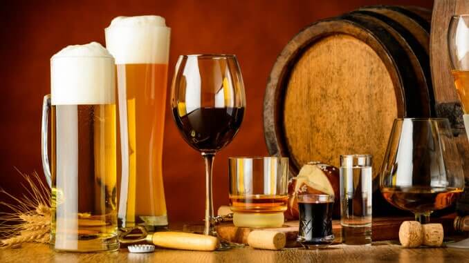 Veganes Bier und veganer Wein liegen im Trend Bier- und Weingläser vor einem Barrique-Fass